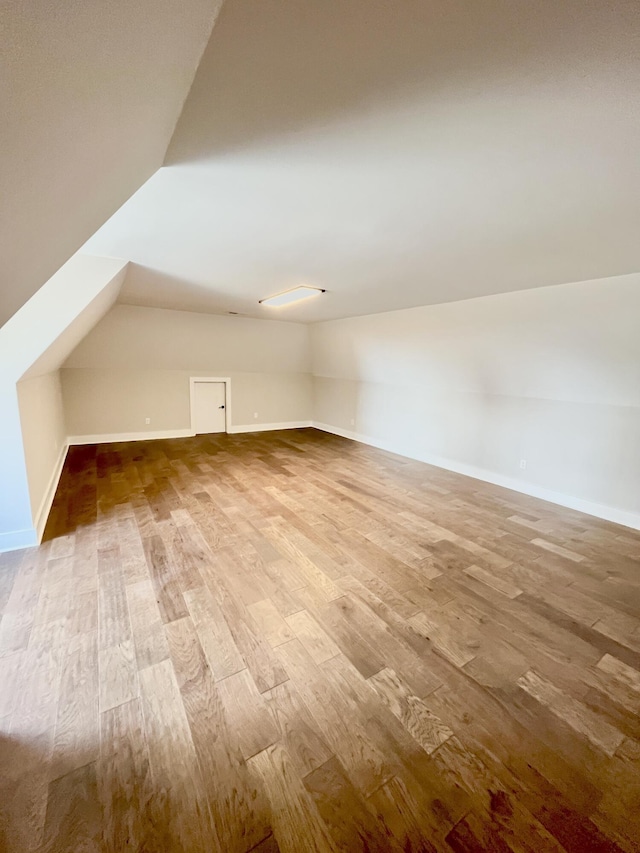 additional living space featuring wood-type flooring and lofted ceiling