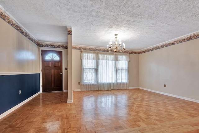 entrance foyer with a textured ceiling, light parquet flooring, ornamental molding, and an inviting chandelier