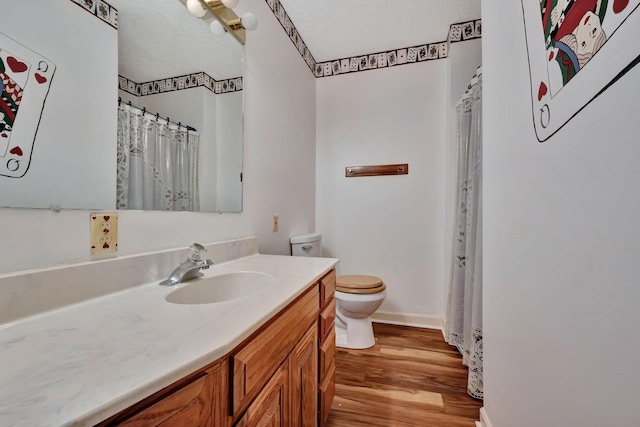 bathroom with a textured ceiling, toilet, vanity, and wood-type flooring