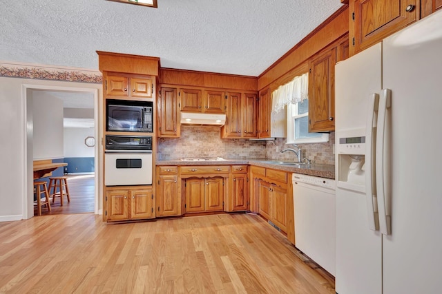 kitchen featuring sink, a textured ceiling, white appliances, light hardwood / wood-style flooring, and backsplash