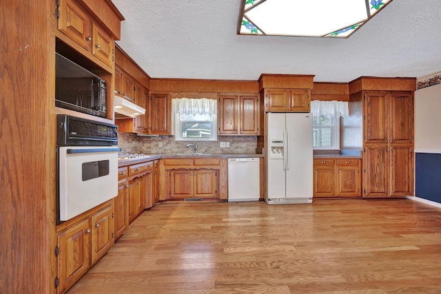 kitchen with sink, a textured ceiling, white appliances, light hardwood / wood-style floors, and backsplash