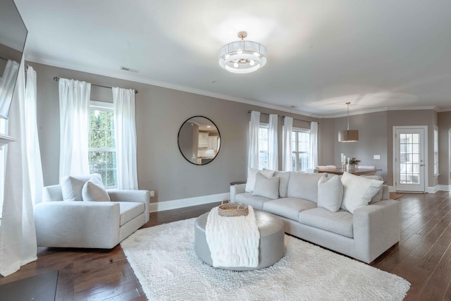 living room with dark hardwood / wood-style flooring, ornamental molding, and a wealth of natural light