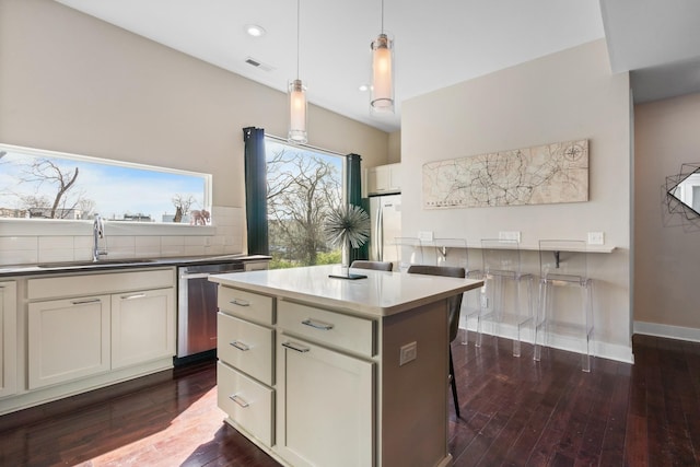 kitchen featuring a center island, sink, appliances with stainless steel finishes, decorative light fixtures, and dark hardwood / wood-style flooring