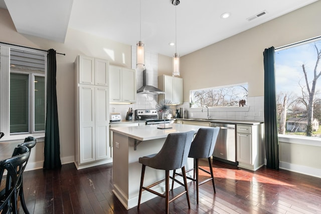 kitchen featuring white cabinetry, a center island, dark hardwood / wood-style floors, a breakfast bar, and appliances with stainless steel finishes