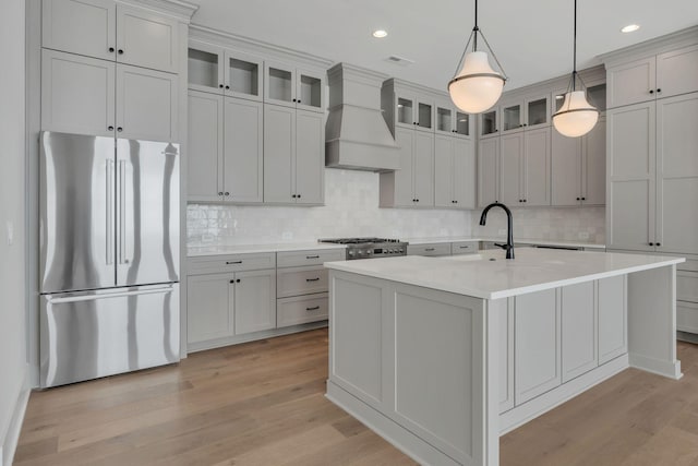 kitchen with a sink, custom exhaust hood, freestanding refrigerator, and light wood-style floors