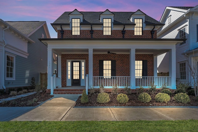 view of front facade with covered porch, a shingled roof, and brick siding