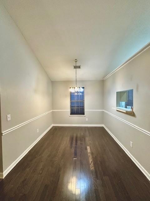 unfurnished dining area featuring dark wood-type flooring and a notable chandelier