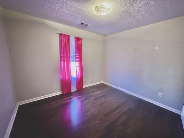 unfurnished room featuring a textured ceiling and dark wood-type flooring