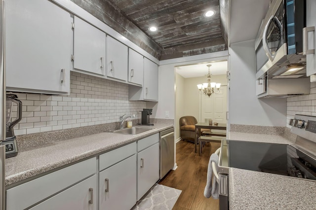 kitchen with sink, dark wood-type flooring, a chandelier, white cabinets, and appliances with stainless steel finishes