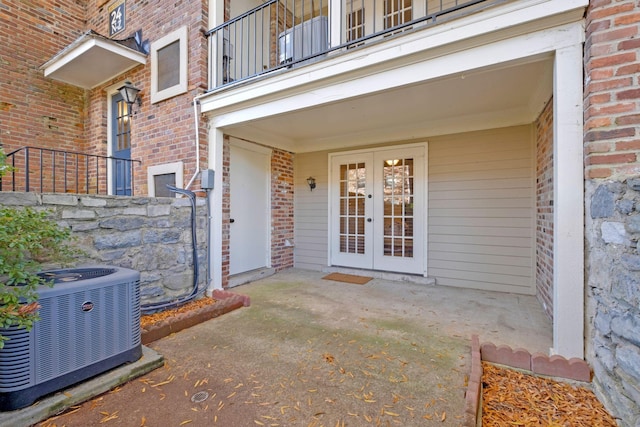 property entrance with cooling unit, a balcony, a patio area, and french doors