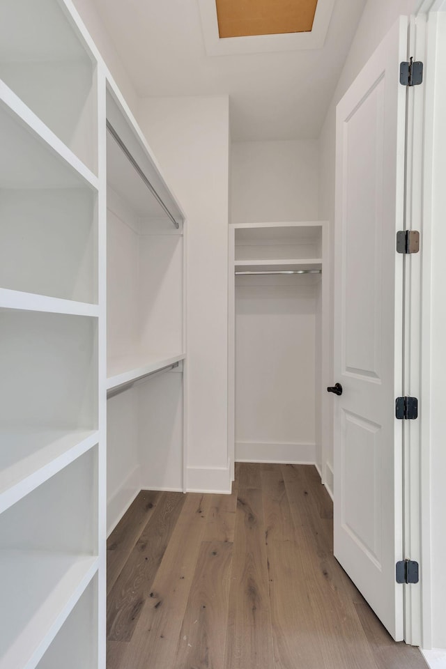 spacious closet with wood finished floors and attic access