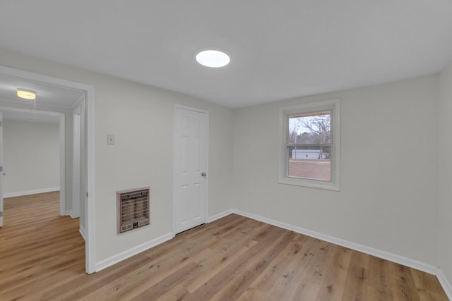 unfurnished room featuring heating unit and light hardwood / wood-style flooring