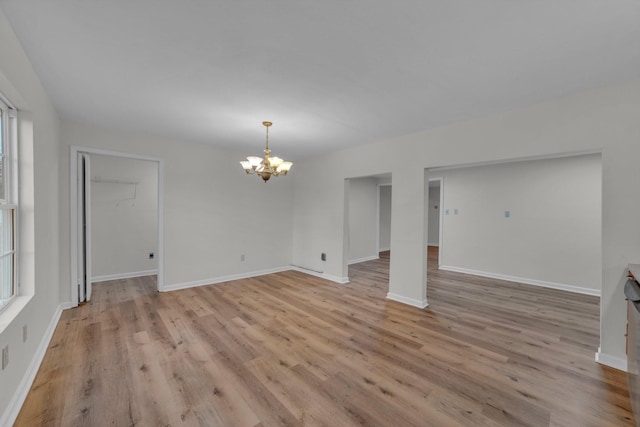 spare room featuring a chandelier and light hardwood / wood-style floors