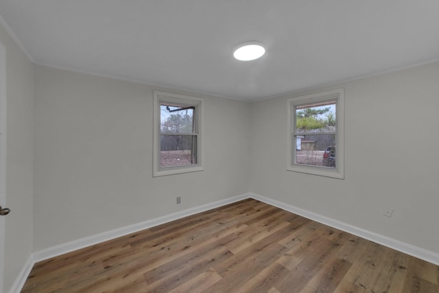 unfurnished room featuring hardwood / wood-style floors, ornamental molding, and a wealth of natural light