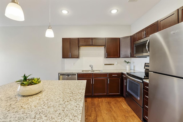 kitchen with sink, hanging light fixtures, tasteful backsplash, light hardwood / wood-style floors, and appliances with stainless steel finishes