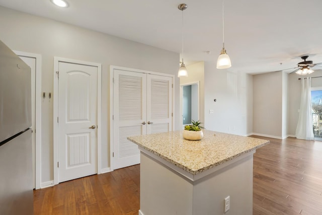 kitchen featuring stainless steel fridge, a center island, hanging light fixtures, and dark wood-type flooring