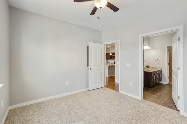 unfurnished bedroom featuring light colored carpet, ensuite bath, and ceiling fan