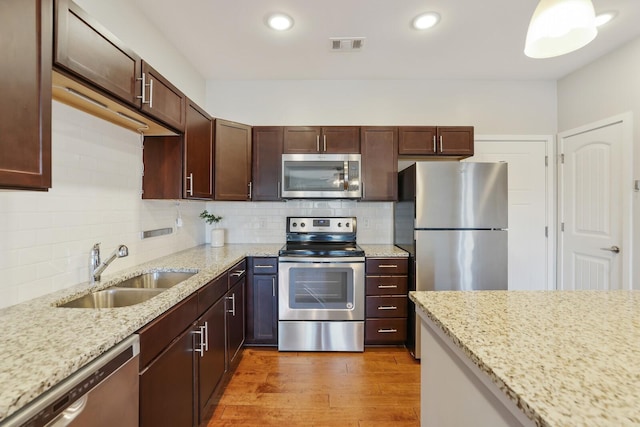 kitchen featuring light stone countertops, sink, light hardwood / wood-style floors, and appliances with stainless steel finishes