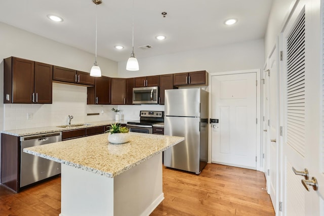 kitchen with a center island, light wood-type flooring, sink, and appliances with stainless steel finishes