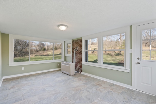 unfurnished sunroom with a healthy amount of sunlight and heating unit