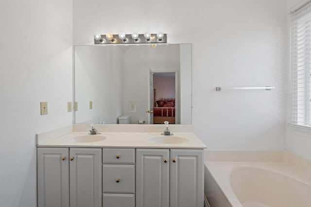 bathroom with a tub, vanity, and toilet