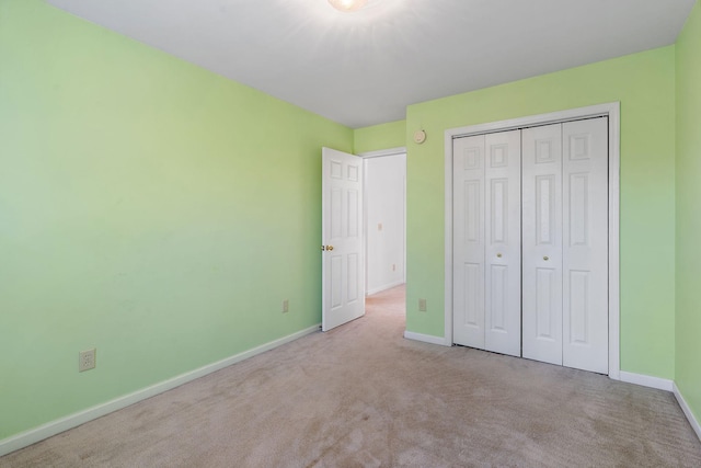 unfurnished bedroom with light colored carpet and a closet