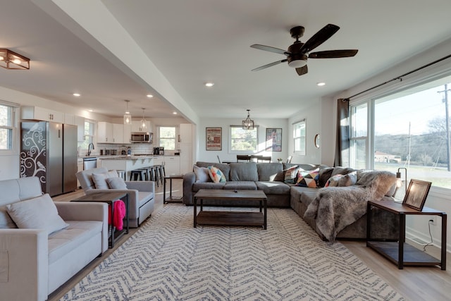 living room featuring ceiling fan, plenty of natural light, sink, and light wood-type flooring