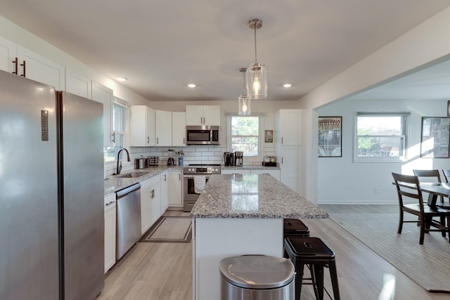 kitchen featuring pendant lighting, a center island, sink, appliances with stainless steel finishes, and light hardwood / wood-style floors