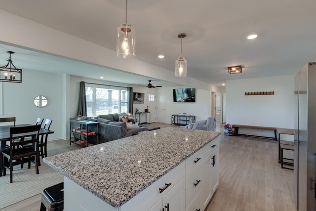 kitchen with white cabinetry, ceiling fan, hanging light fixtures, and light hardwood / wood-style floors