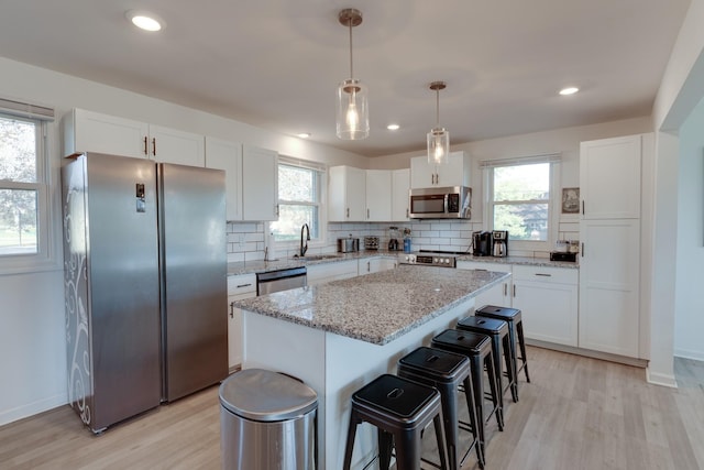 kitchen featuring a center island, white cabinetry, stainless steel appliances, and a wealth of natural light