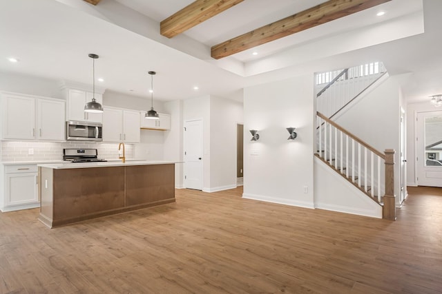 kitchen featuring white cabinets, stainless steel appliances, light hardwood / wood-style flooring, and an island with sink