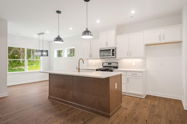 kitchen with white cabinets, dark hardwood / wood-style flooring, stainless steel appliances, and a center island with sink