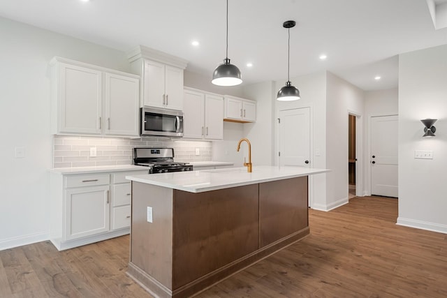 kitchen featuring white cabinetry, light hardwood / wood-style flooring, an island with sink, decorative backsplash, and appliances with stainless steel finishes