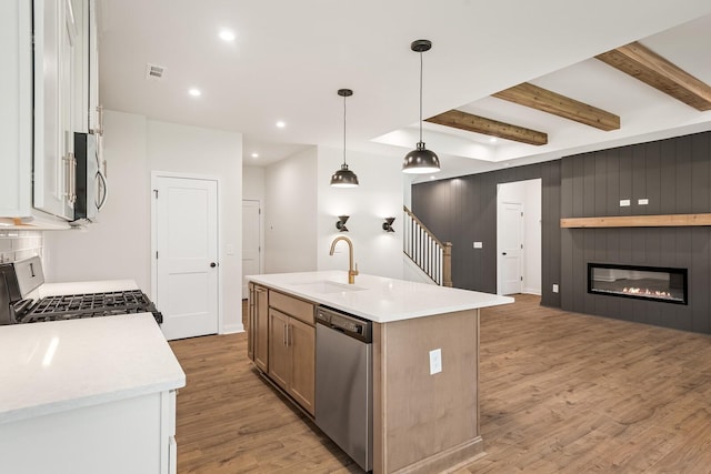 kitchen featuring a kitchen island with sink, sink, decorative light fixtures, white cabinetry, and stainless steel appliances