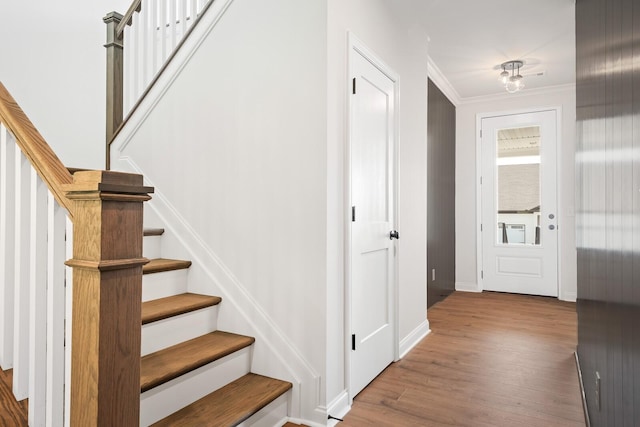 stairs with wood-type flooring and ornamental molding