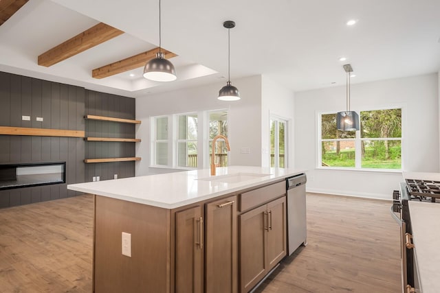 kitchen with appliances with stainless steel finishes, sink, pendant lighting, light hardwood / wood-style flooring, and a center island