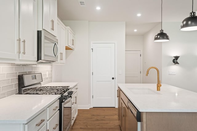 kitchen featuring white cabinetry, sink, an island with sink, decorative light fixtures, and appliances with stainless steel finishes