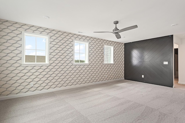 unfurnished room featuring light carpet, ceiling fan, and wooden walls