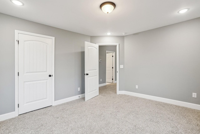 unfurnished bedroom with light colored carpet and a closet