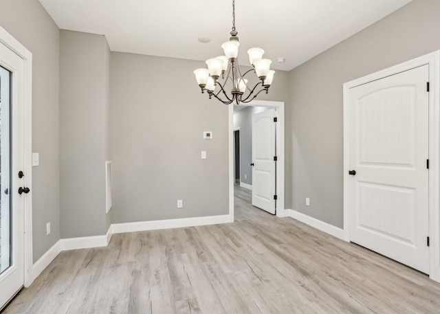 unfurnished dining area featuring light hardwood / wood-style flooring and a notable chandelier