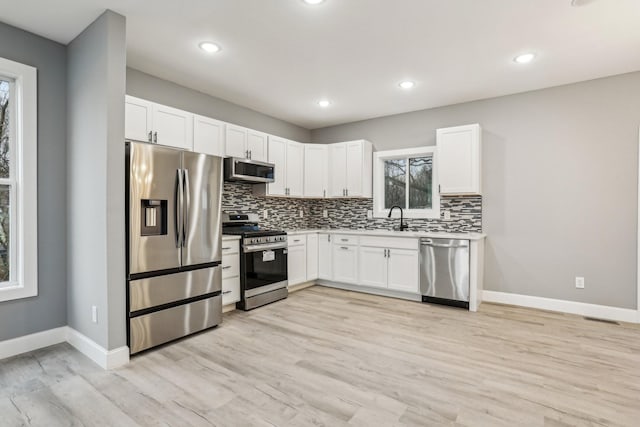 kitchen with white cabinetry, stainless steel appliances, and light hardwood / wood-style floors