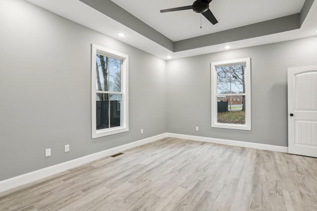 spare room with ceiling fan, light hardwood / wood-style floors, and a raised ceiling