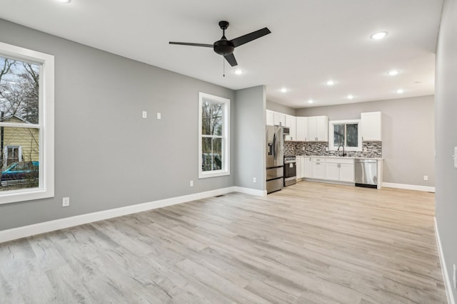 unfurnished living room featuring ceiling fan, sink, and light hardwood / wood-style flooring