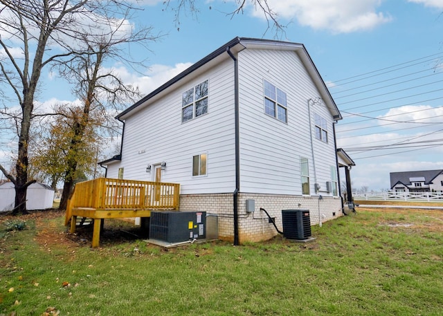 back of property with a deck, a yard, and central air condition unit