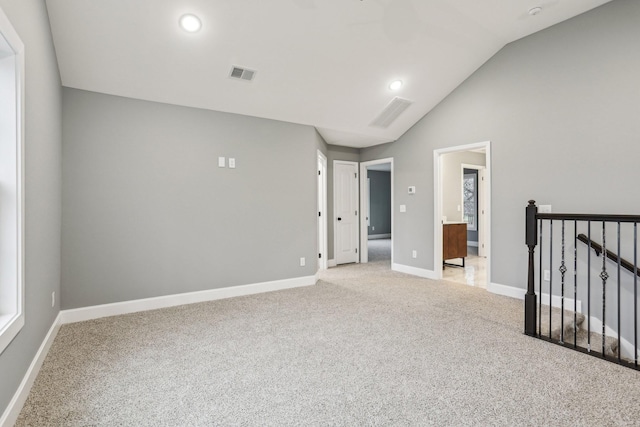 spare room with light colored carpet and vaulted ceiling