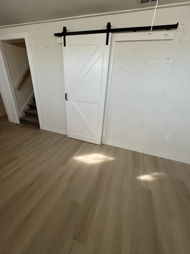 unfurnished bedroom featuring a barn door and wood-type flooring