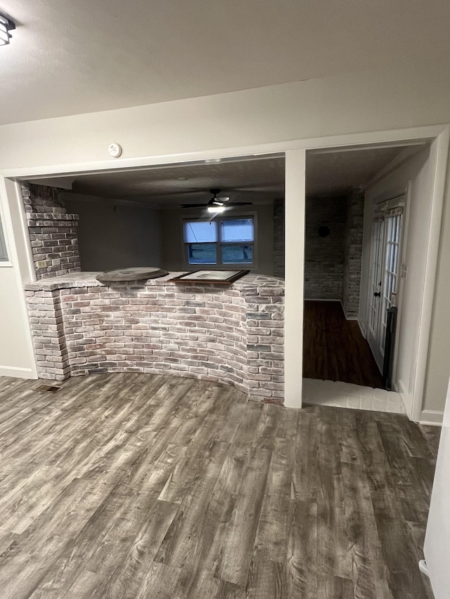 basement with hardwood / wood-style flooring and brick wall