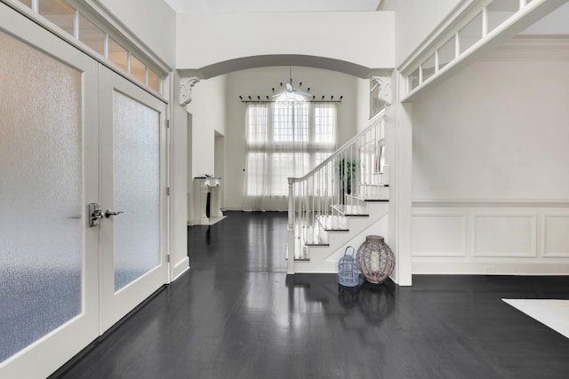 foyer with a high ceiling, dark hardwood / wood-style floors, french doors, and ornamental molding