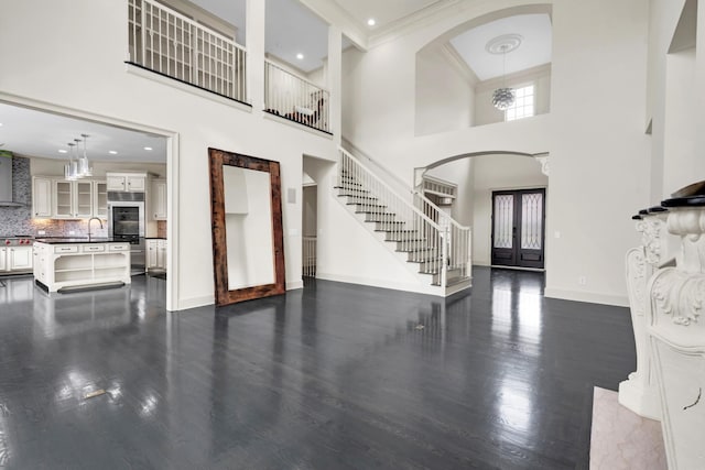 foyer with french doors, sink, a high ceiling, dark hardwood / wood-style flooring, and crown molding