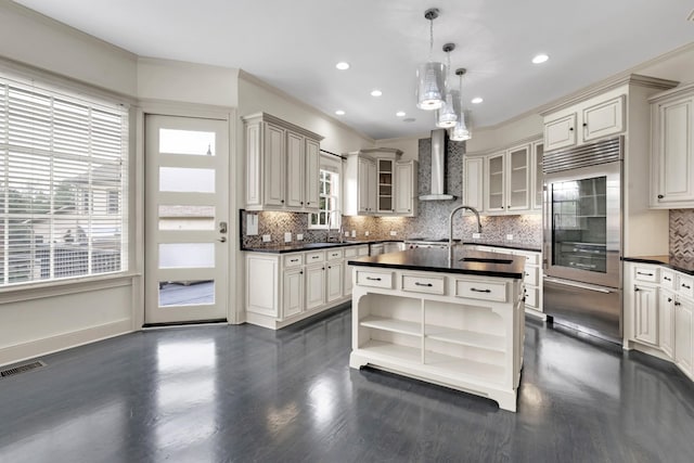 kitchen with pendant lighting, tasteful backsplash, ornamental molding, and wall chimney exhaust hood